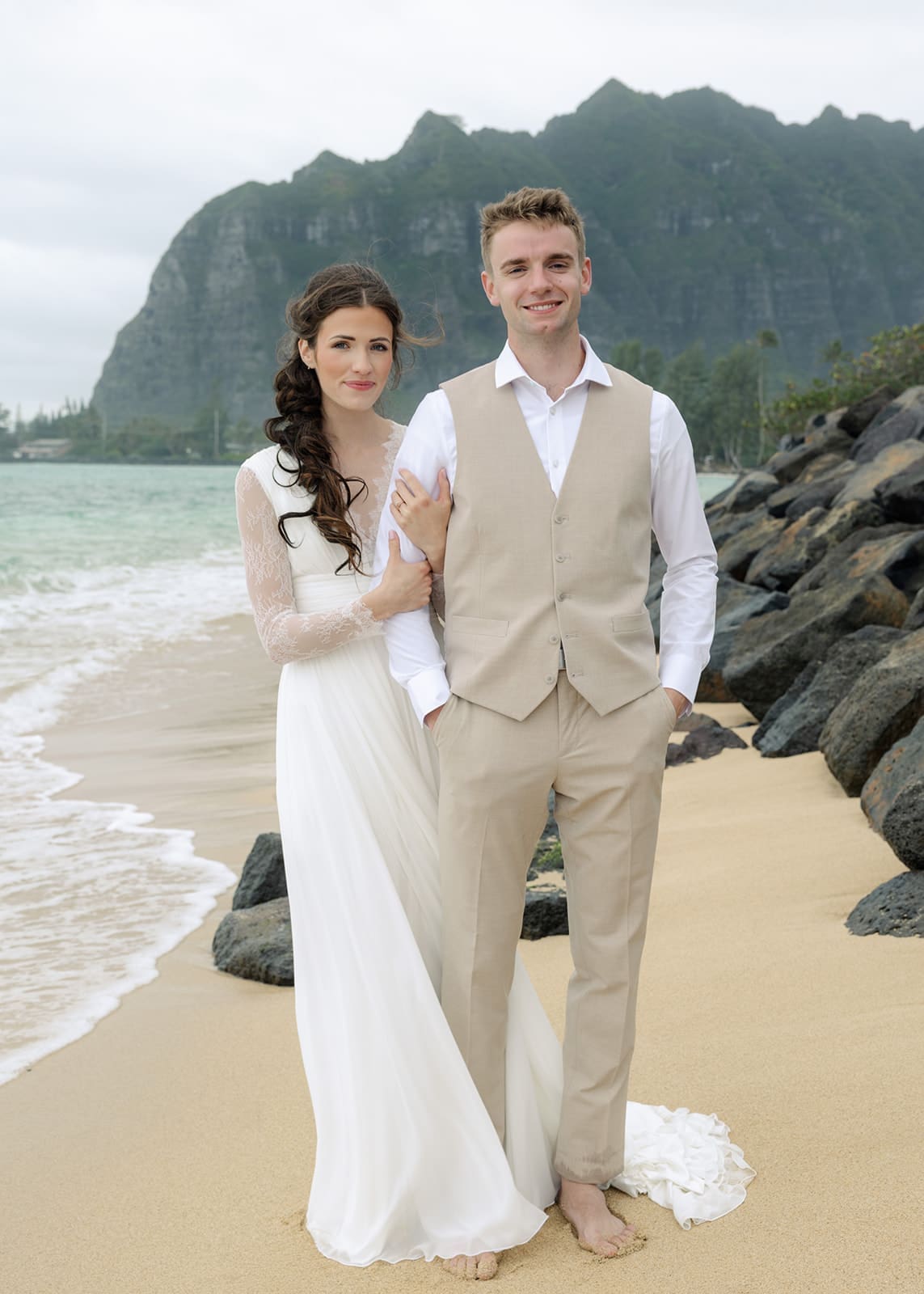Couple standing on a beach in Oahu, Hawaii after getting married